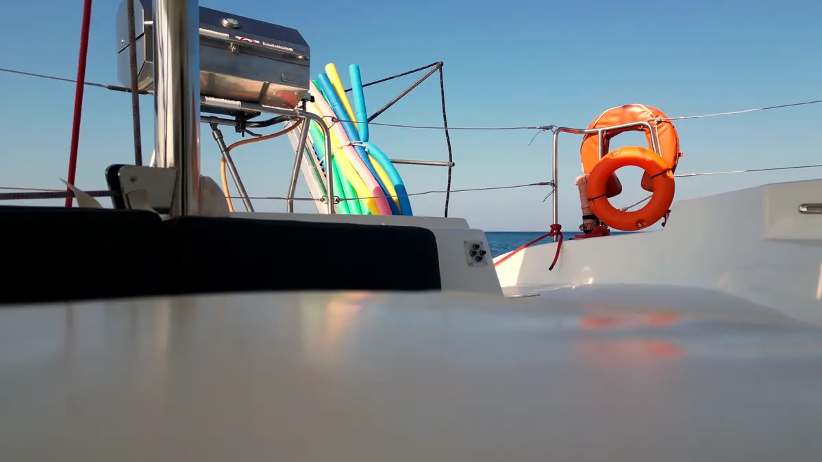 Paddleboards and the life ring on the catamaran's deck before a boat-tour day