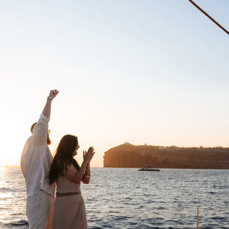 Champagne opened on deck as the sun drops behind the caldera