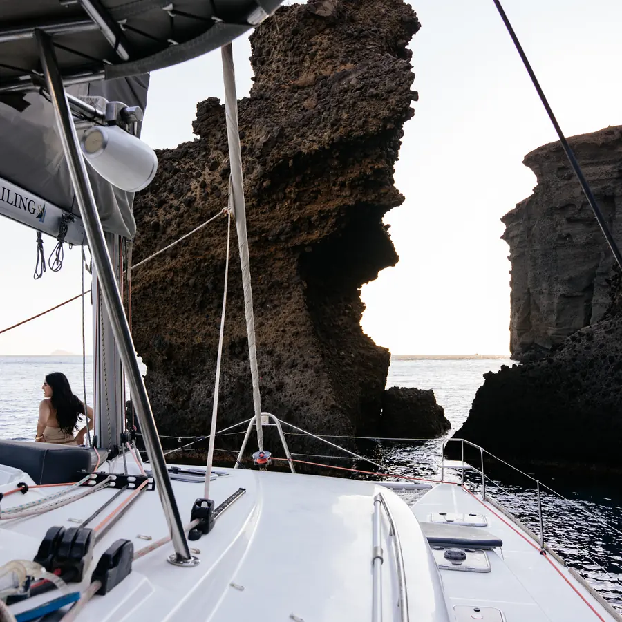 The catamaran's foredeck beneath the caldera cliffs between stops