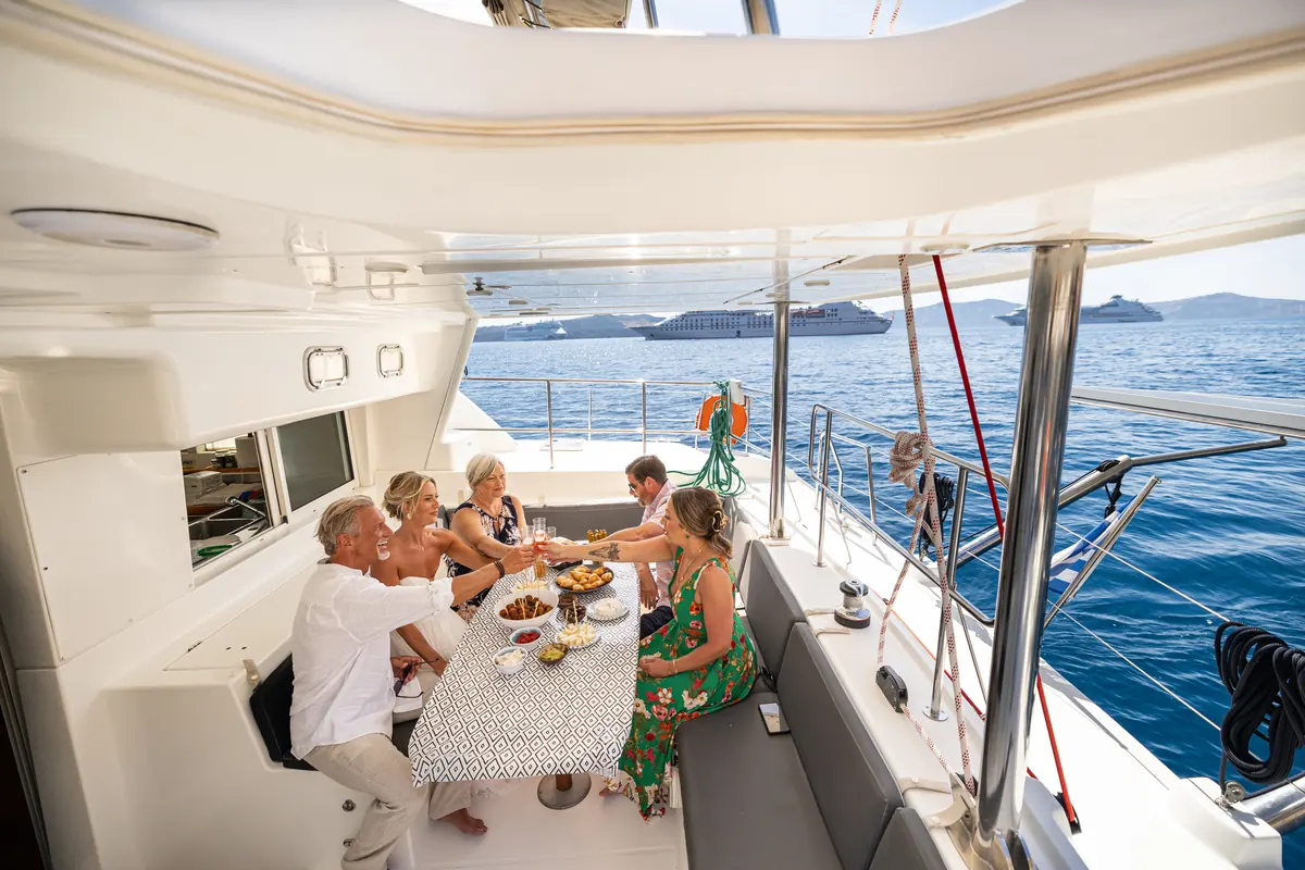 Guests laughing over lunch at the catamaran's cockpit table