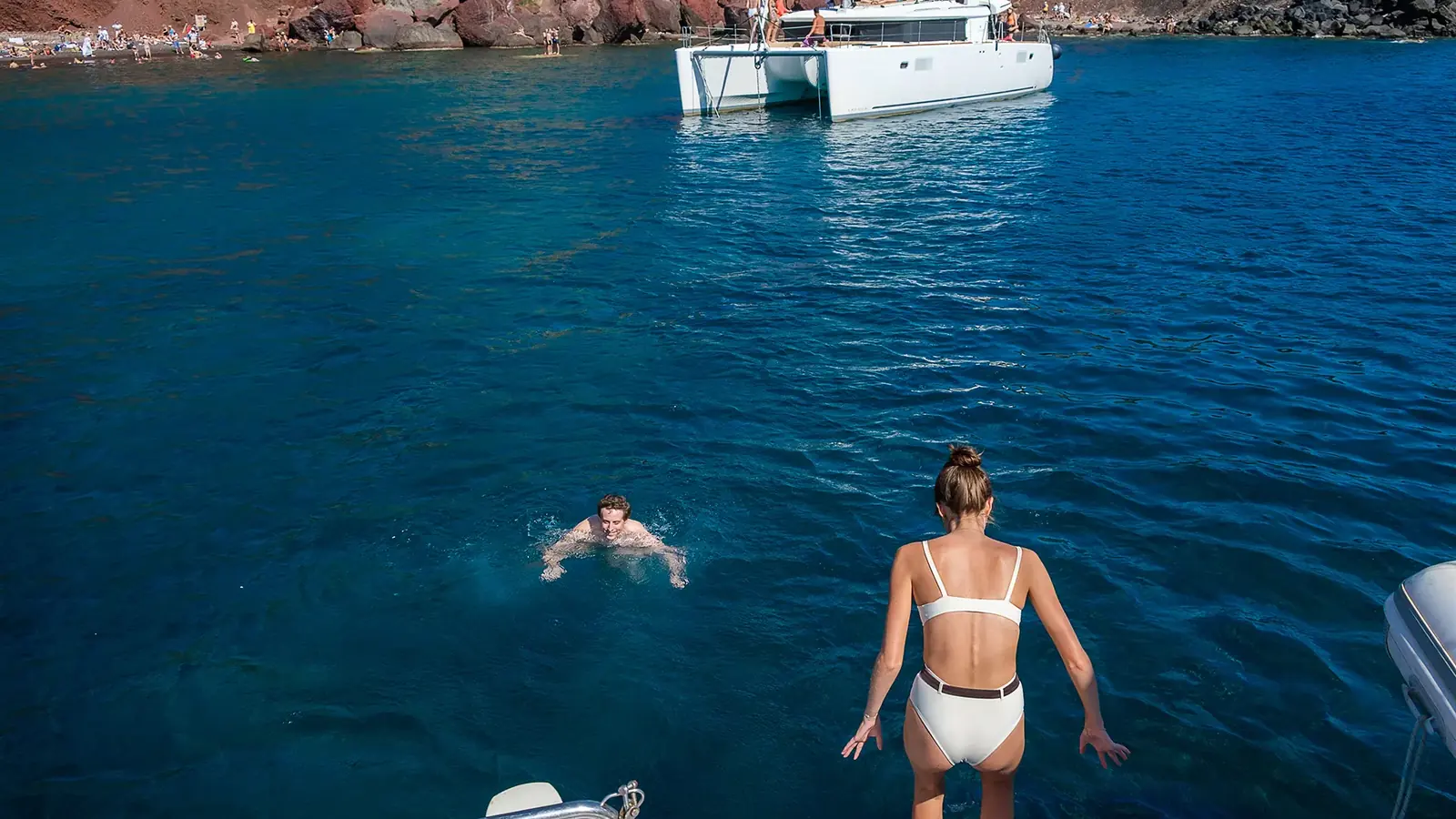 Daytime catamaran cruise anchored over turquoise swim-stop water in the Santorini caldera