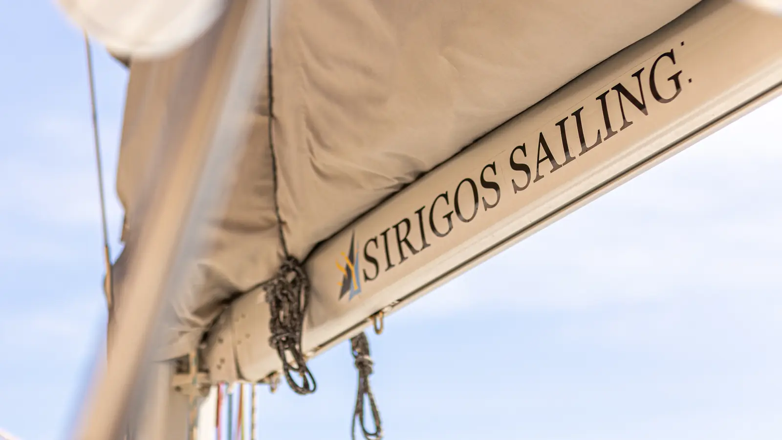 The Sirigos Sailing name stitched into the boom cover of the family catamaran, caldera sky beyond