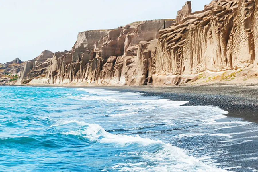 The sculpted white cliffs and dark sand of Vlychada on Santorini's south coast